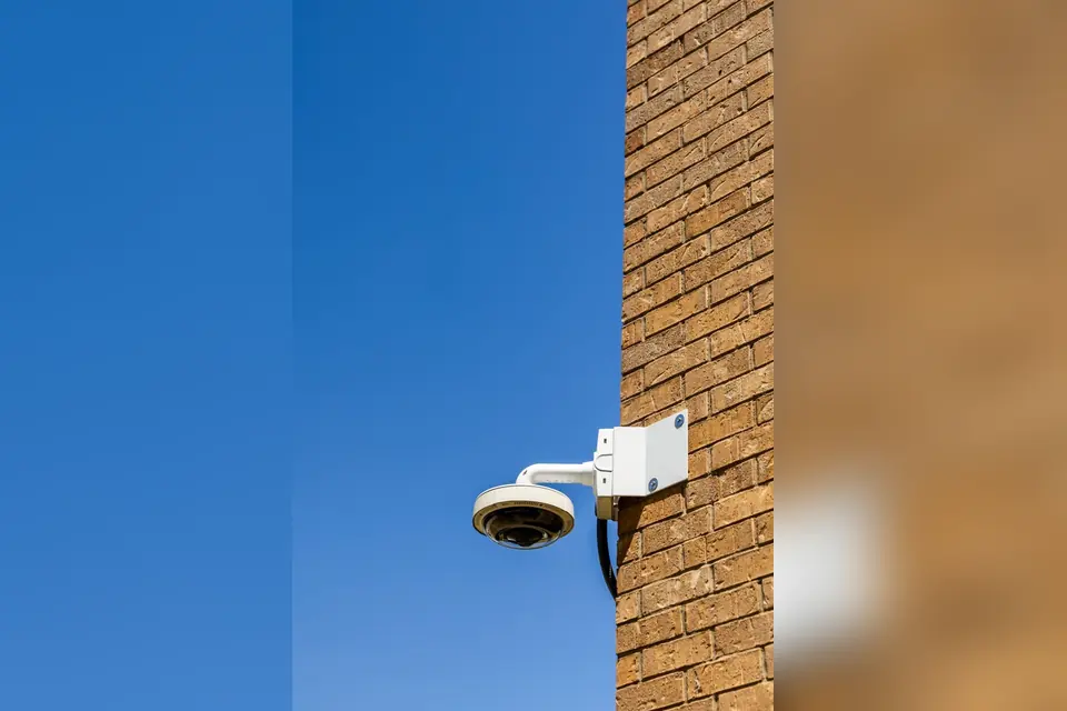 Security Camera on Brick Wall with Clear Sky
