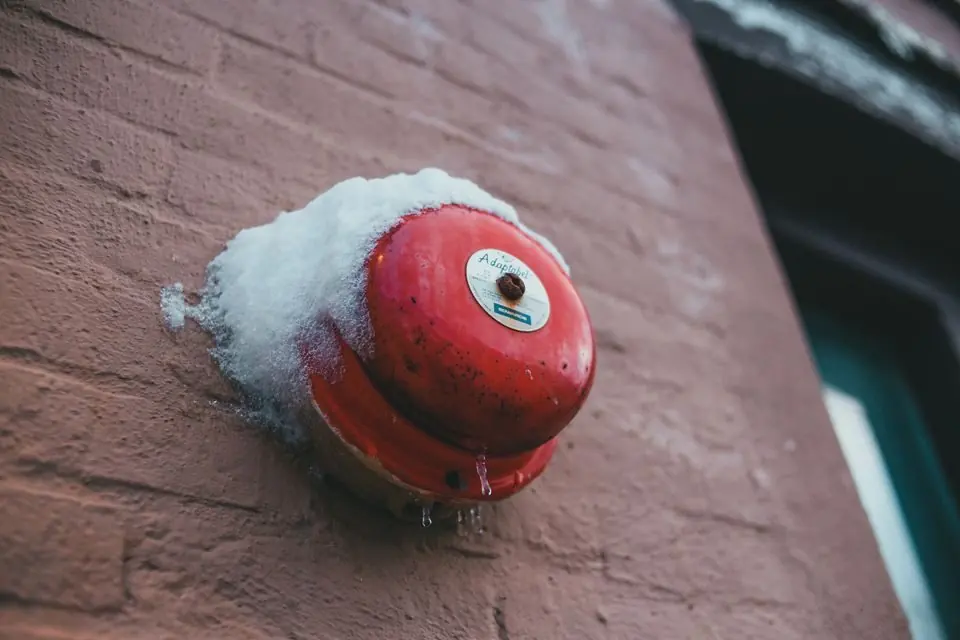 Fire alarm button on brick wall of building in winter
